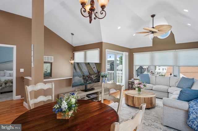 living area with ceiling fan with notable chandelier, wood finished floors, visible vents, and high vaulted ceiling