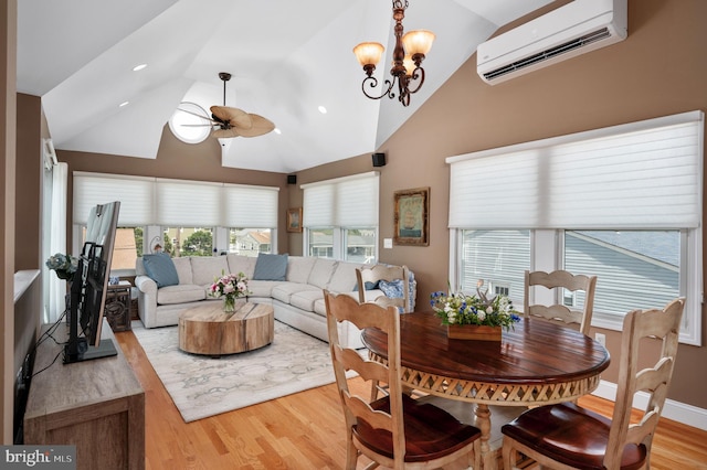 dining room with wood finished floors, baseboards, high vaulted ceiling, a wall mounted AC, and ceiling fan with notable chandelier