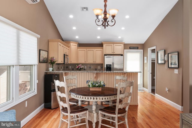 dining area with visible vents, lofted ceiling, a chandelier, and light wood finished floors