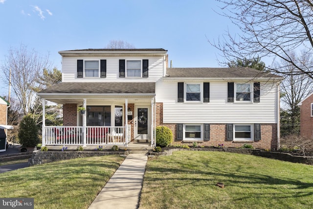 tri-level home featuring a front yard, covered porch, and brick siding