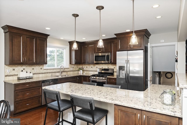 kitchen featuring appliances with stainless steel finishes, tasteful backsplash, dark brown cabinetry, and a sink