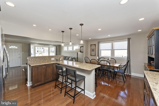 kitchen featuring a kitchen bar, recessed lighting, freestanding refrigerator, and dark wood finished floors