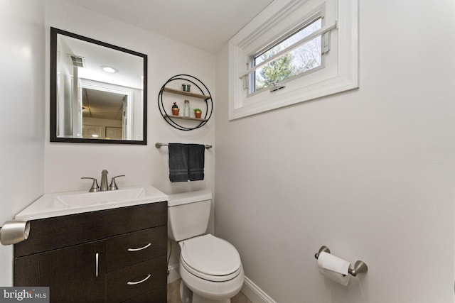 half bath with baseboards, visible vents, toilet, and vanity
