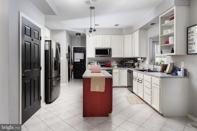 kitchen featuring a center island, light countertops, appliances with stainless steel finishes, white cabinetry, and a sink