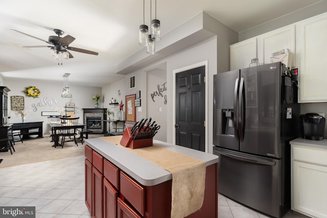 kitchen featuring a glass covered fireplace, stainless steel fridge, light tile patterned floors, dark brown cabinets, and ceiling fan
