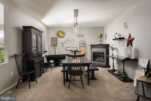 dining space with a fireplace, light colored carpet, and baseboards