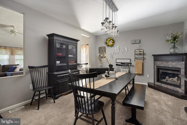dining room featuring visible vents, baseboards, carpet, ceiling fan, and a glass covered fireplace
