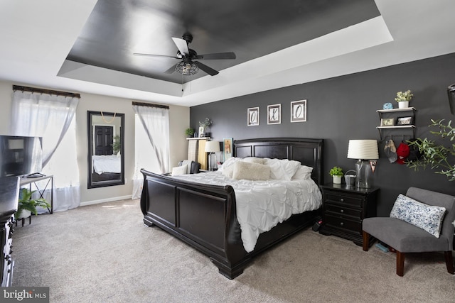 carpeted bedroom with baseboards, a raised ceiling, and ceiling fan