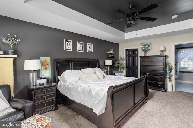 bedroom with a raised ceiling, ceiling fan, and carpet floors