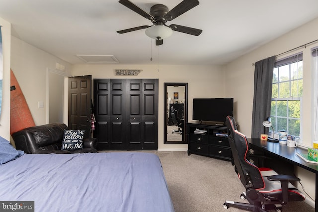 carpeted bedroom with a closet, attic access, and a ceiling fan