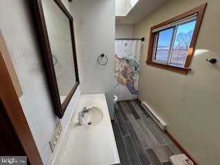 bathroom with vanity, a shower with curtain, wood finished floors, toilet, and baseboard heating