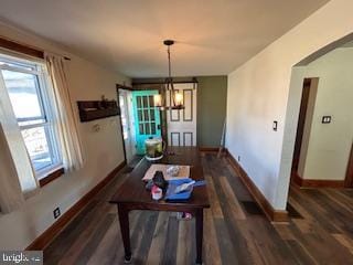 dining space with baseboards, wood finished floors, and a chandelier