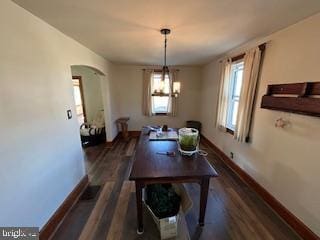 dining space with dark wood-type flooring, arched walkways, baseboards, and a chandelier