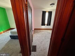 hall featuring visible vents, baseboards, and carpet flooring