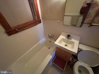 bathroom featuring a tub, toilet, and vanity