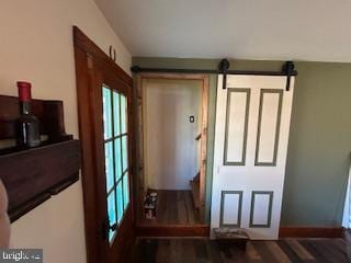 doorway featuring baseboards, a barn door, and wood finished floors