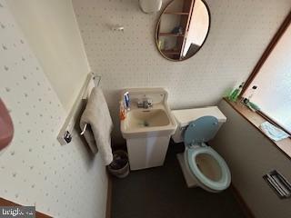 half bath with toilet and wallpapered walls