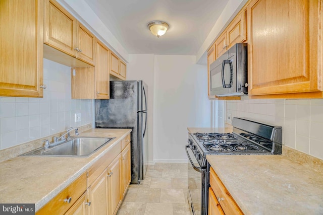 kitchen with tasteful backsplash, baseboards, a sink, light countertops, and black appliances