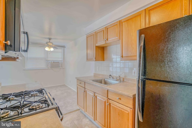 kitchen with stainless steel range with gas cooktop, ceiling fan, freestanding refrigerator, tasteful backsplash, and a sink