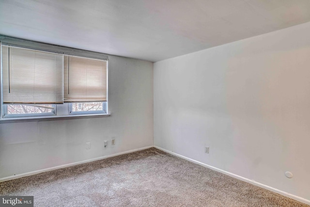 carpeted empty room featuring baseboards
