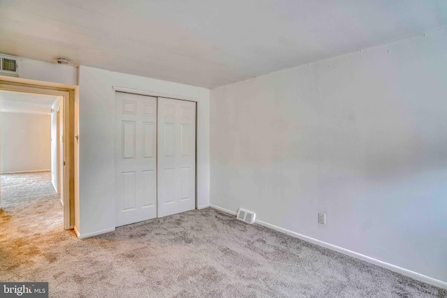 unfurnished bedroom with carpet flooring, visible vents, a closet, and baseboards