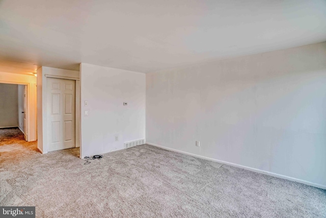 spare room featuring carpet flooring, visible vents, and baseboards