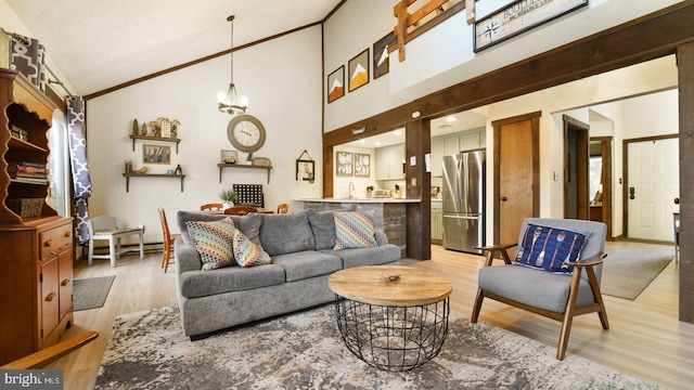 living room with light wood-type flooring, high vaulted ceiling, a chandelier, and crown molding