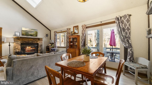 dining space with high vaulted ceiling, a fireplace, and light wood finished floors