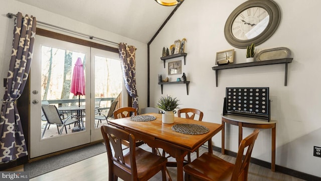 dining space with vaulted ceiling, wood finished floors, and baseboards