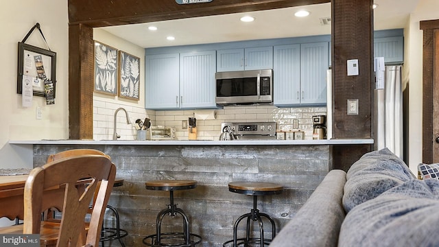 kitchen with a sink, backsplash, appliances with stainless steel finishes, and recessed lighting