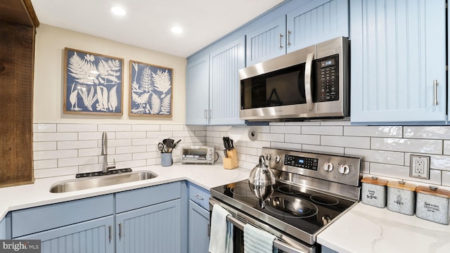 kitchen featuring a sink, light countertops, backsplash, and stainless steel appliances