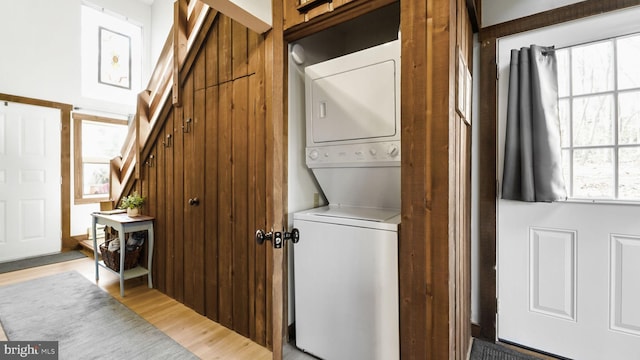 laundry room with light wood-type flooring and stacked washing maching and dryer