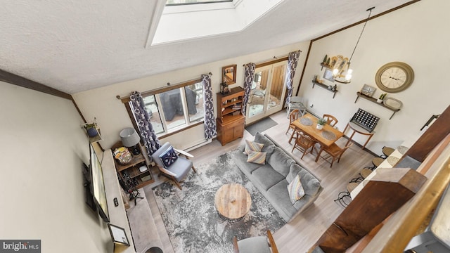 living room featuring vaulted ceiling with skylight, a textured ceiling, and wood finished floors