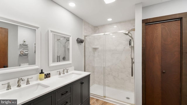 full bath with a shower stall, wood finished floors, double vanity, and a sink