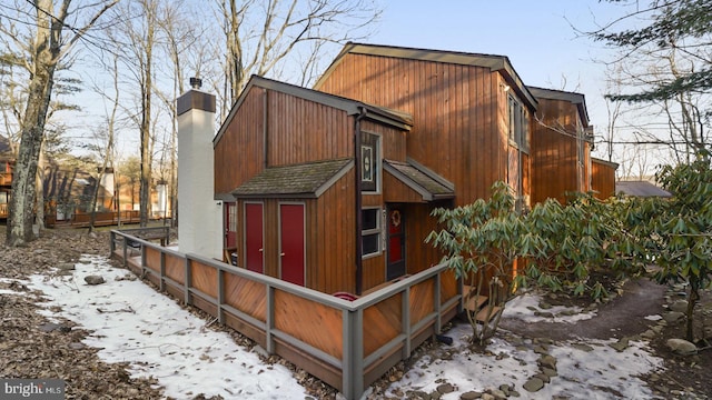 view of side of home featuring a barn, a chimney, and a shingled roof