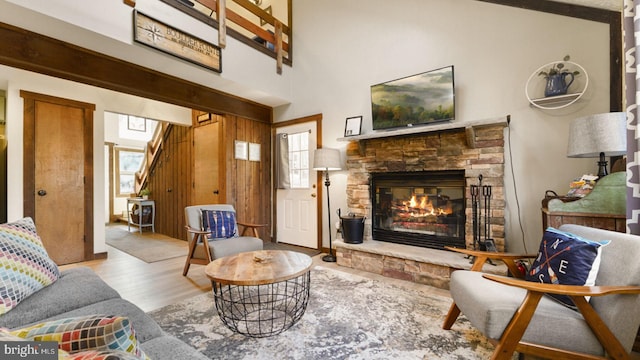 living area featuring a stone fireplace, stairs, and wood finished floors