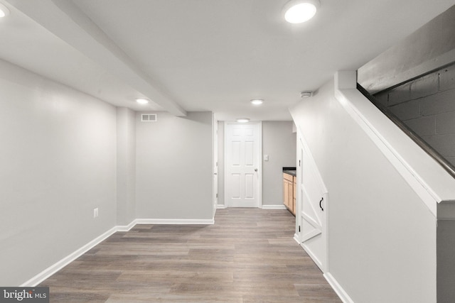 finished below grade area with baseboards, light wood-style flooring, and visible vents