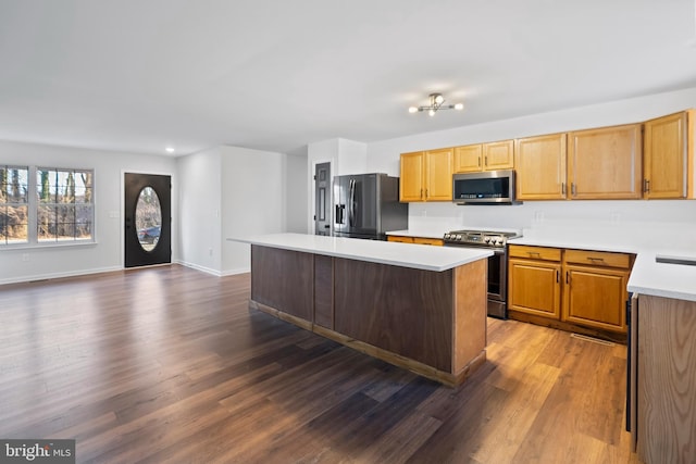 kitchen featuring a kitchen island, dark wood-style floors, appliances with stainless steel finishes, light countertops, and baseboards