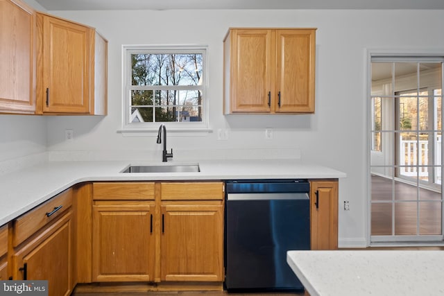 kitchen featuring dishwashing machine, light countertops, and a sink