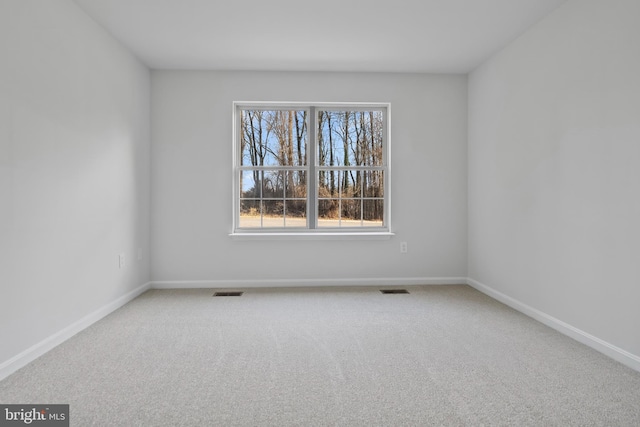 carpeted spare room featuring visible vents and baseboards