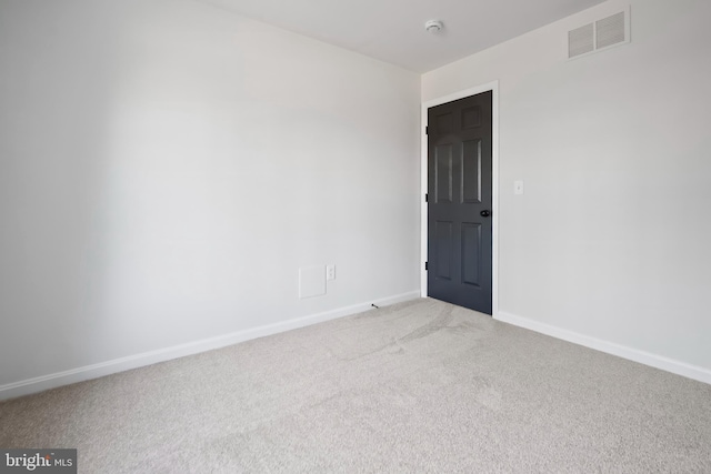 empty room with baseboards, visible vents, and light carpet