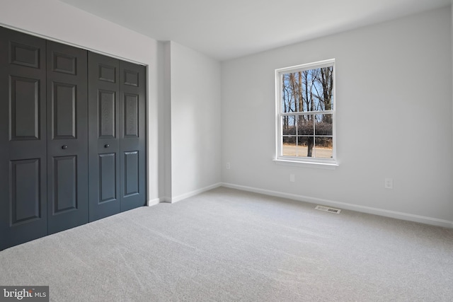 unfurnished bedroom featuring a closet, visible vents, baseboards, and carpet