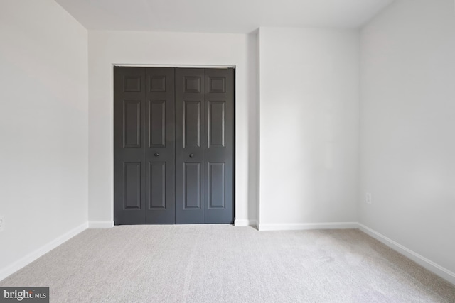 unfurnished bedroom with carpet, baseboards, and a closet