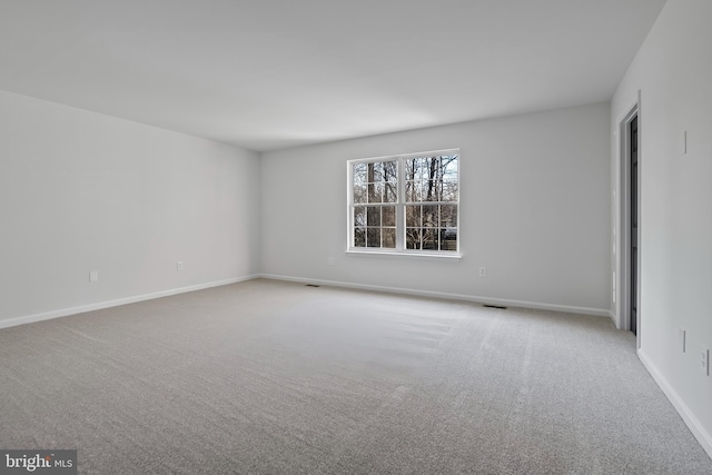 carpeted empty room featuring visible vents and baseboards