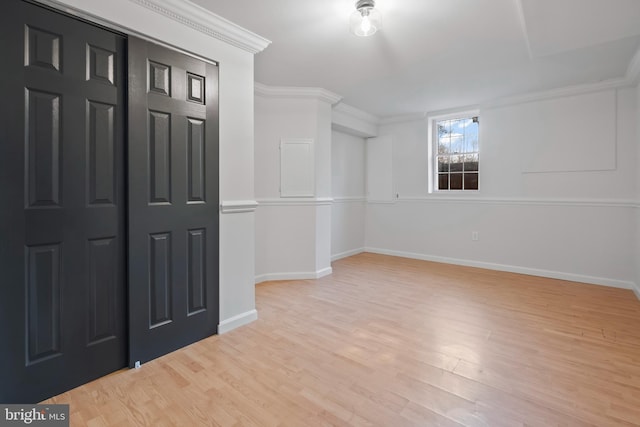 empty room featuring baseboards, wood finished floors, and crown molding