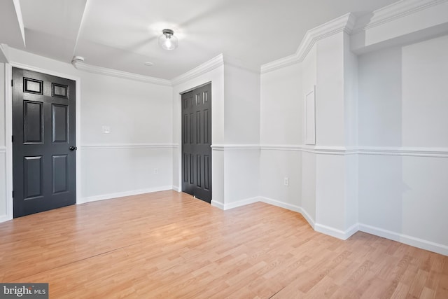 empty room featuring wood finished floors, baseboards, and ornamental molding