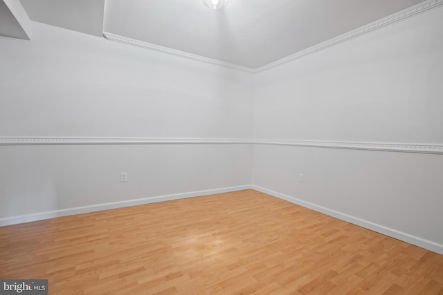 empty room with crown molding, baseboards, and wood finished floors