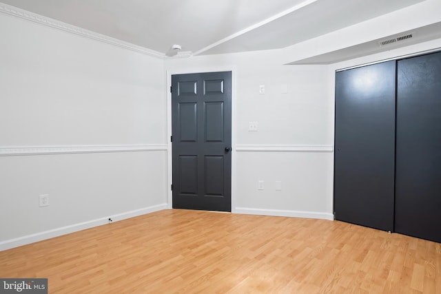 unfurnished bedroom with a closet, baseboards, visible vents, and wood finished floors