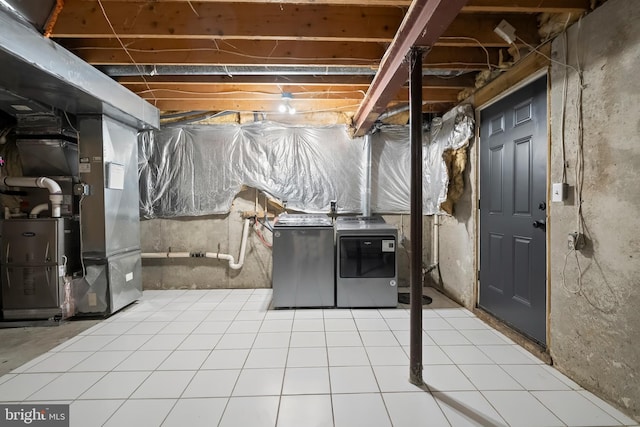 unfinished basement featuring fridge, heating unit, tile patterned flooring, and washing machine and clothes dryer