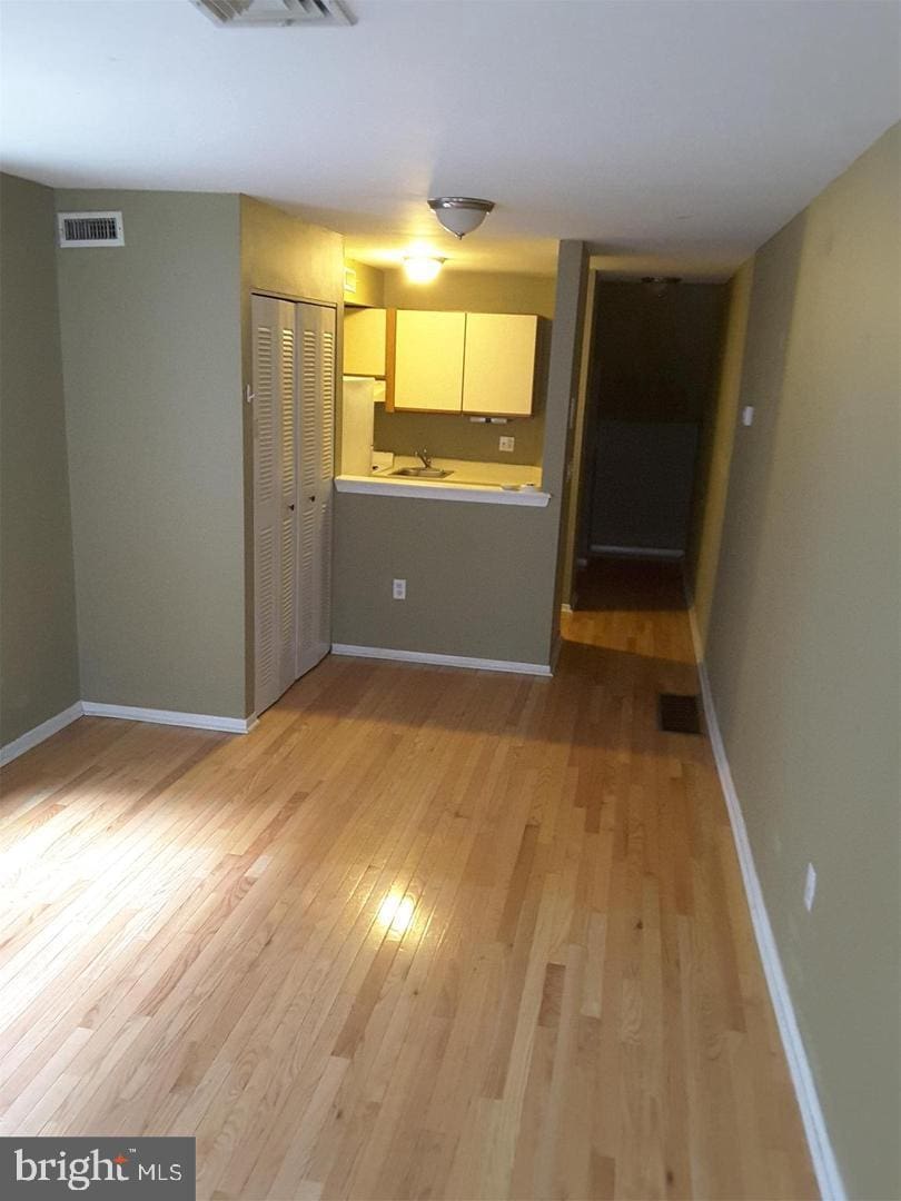 unfurnished living room with light wood-type flooring, visible vents, and baseboards